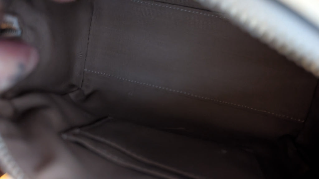 Close-up view of the interior lining of a dark brown leather or faux-leather pouch or bag, showing stitched interior panels and zipper tape. Pre-Owned Coach Rowan Cherry Print Leather Crossbody / Mini Satchel – Chalk Multi