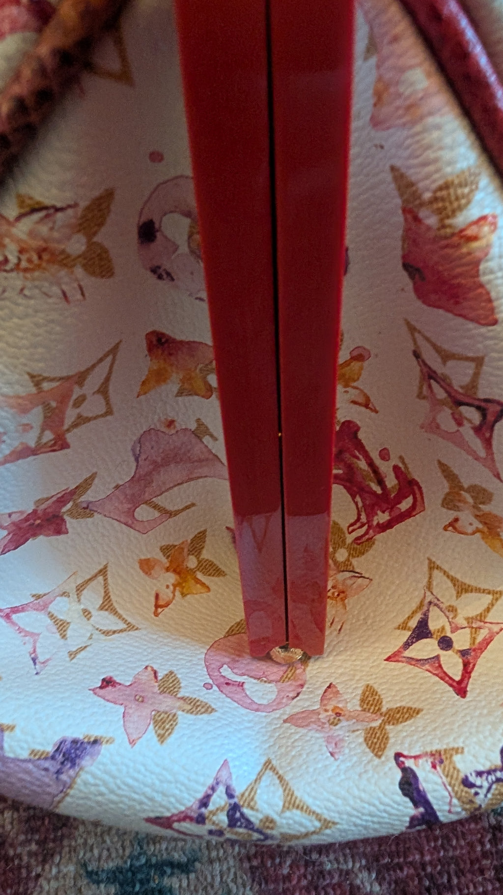 Close-up of a Louis Vuitton handbag featuring the brand's classic monogram pattern in pink, gold, and red on a cream-colored leather, with a prominent glossy red vertical divider or strap in the center. Pre-Owned Louis Vuitton x Richard Prince Limited Edition Monogram Aquarelle Watercolor Frame Speedy 30 – 2008