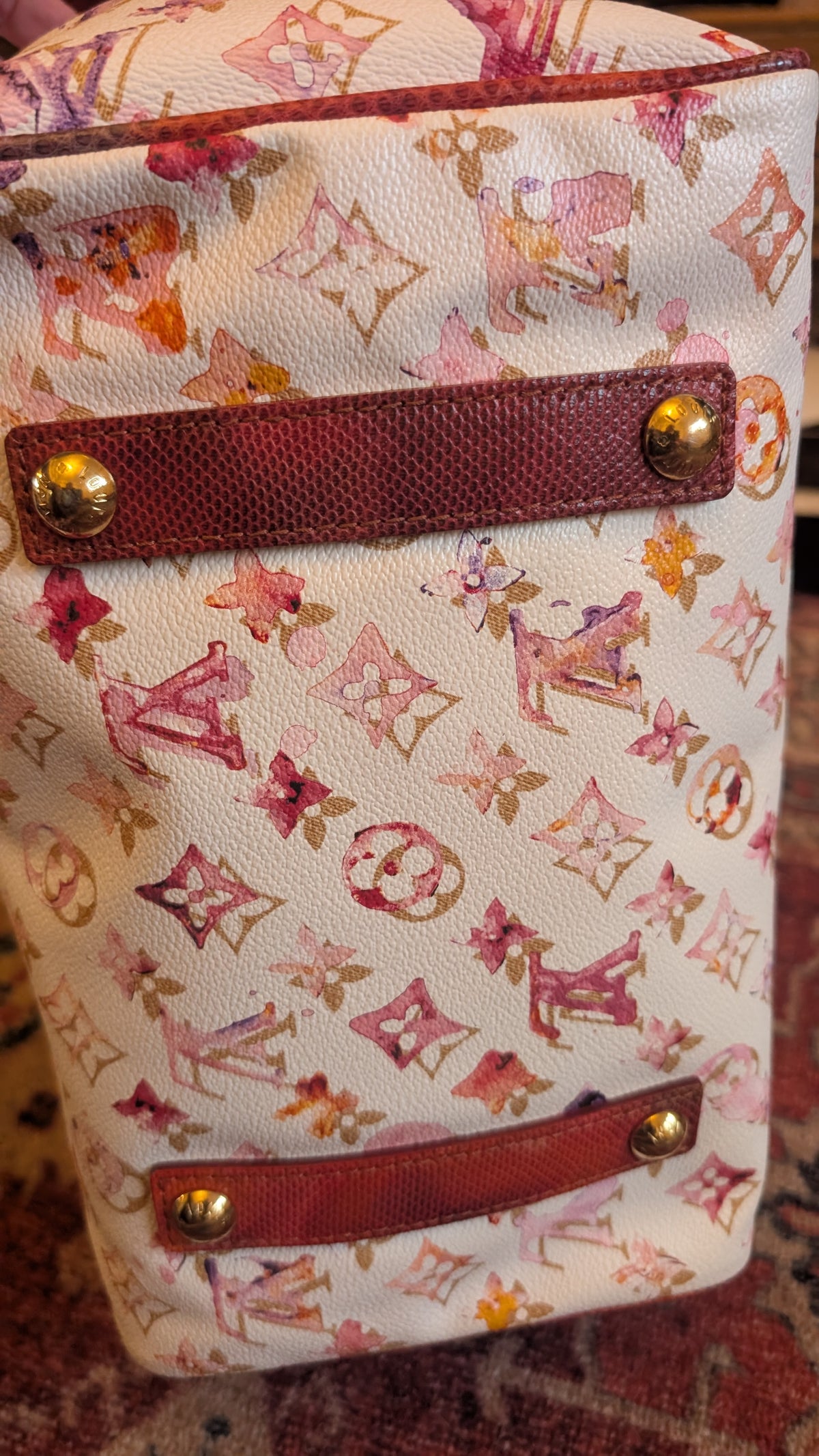 A close-up of a Louis Vuitton monogram canvas bag in pink and orange tones, featuring dark red textured leather trim and gold-tone metal studs. Pre-Owned Louis Vuitton x Richard Prince Limited Edition Monogram Aquarelle Watercolor Frame Speedy 30 – 2008