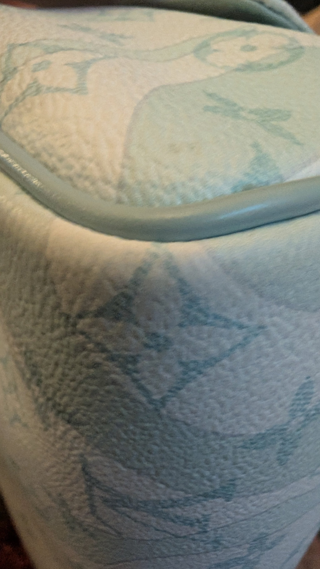 A close-up of a light blue and white textured leather bag with a subtle monogram pattern and a light blue trim. Pre-Owned Louis Vuitton x Richard Prince Limited Edition Monogram Bag – Spring/Summer 2008 – Pale Blue