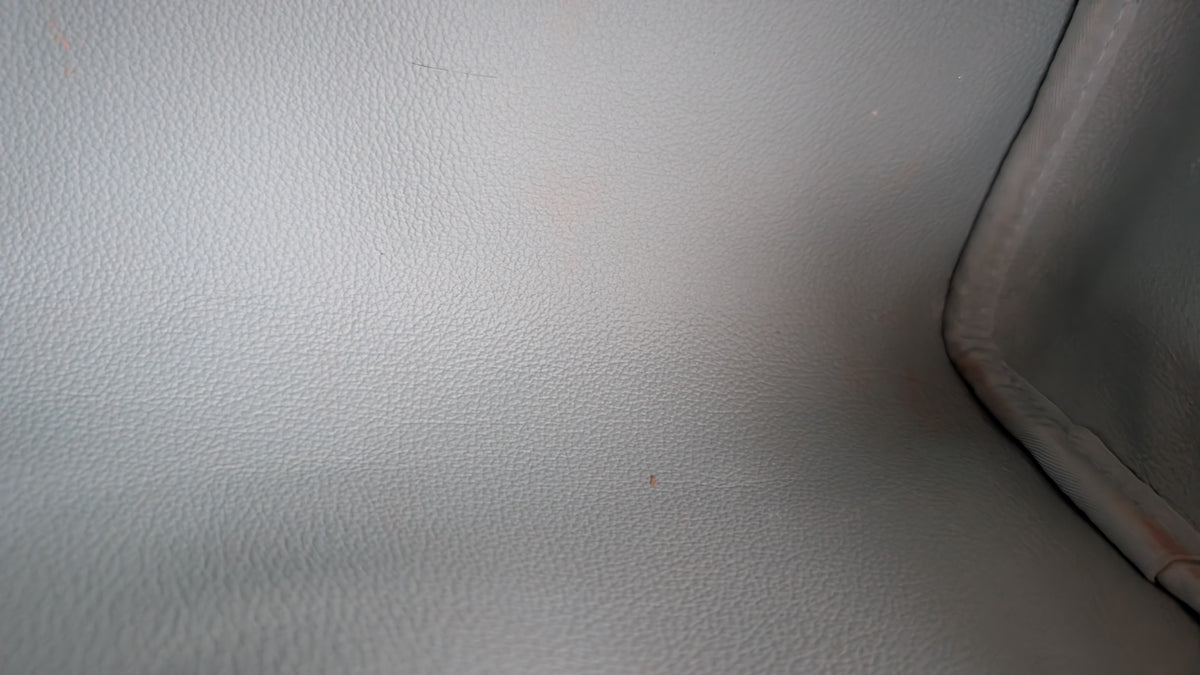 Close-up of a light gray textured material corner with a darker seam along the right edge. Pre-Owned Louis Vuitton x Richard Prince Limited Edition Monogram Bag – Spring/Summer 2008 – Pale Blue