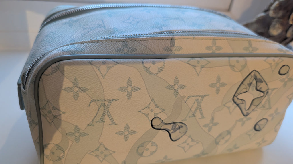 A Louis Vuitton toiletry bag in light blue and cream monogram canvas, photographed on a white surface. Pre-Owned Louis Vuitton x Richard Prince Limited Edition Monogram Bag – Spring/Summer 2008 – Pale Blue