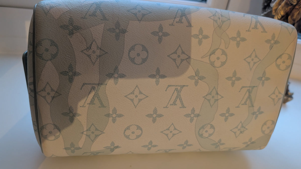 A Louis Vuitton monogram canvas pouch or small bag, photographed on a light surface. The item has an off-white/cream base with gray monogram motifs and a noticeable light reflection across the front. Pre-Owned Louis Vuitton x Richard Prince Limited Edition Monogram Bag – Spring/Summer 2008 – Pale Blue