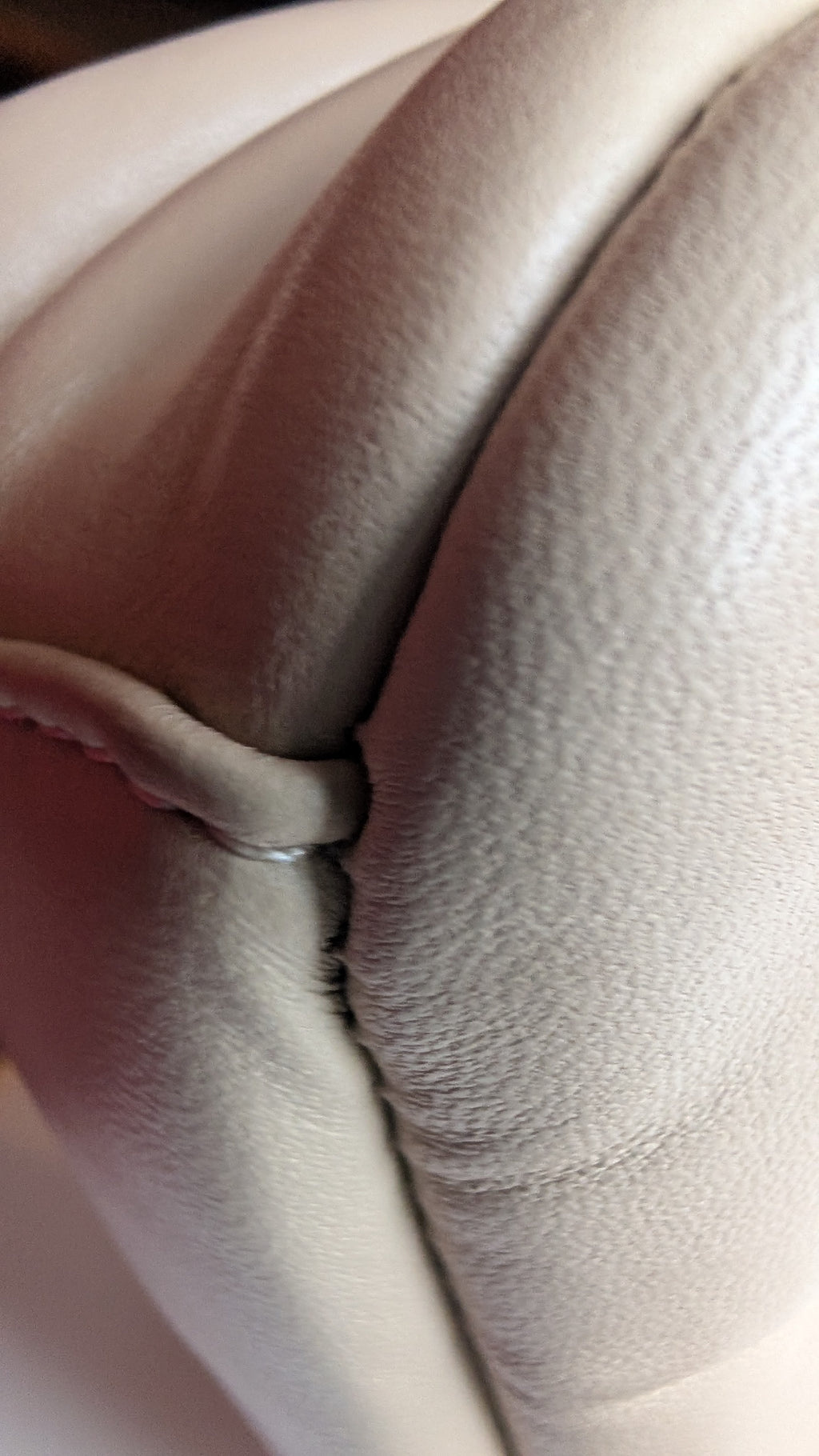 Close-up of a light cream leather  bag showing the textured grain and stitched seam details. Pre-Owned Coach Pillow Tabby Shoulder Bag – Cream/Ivory Leather