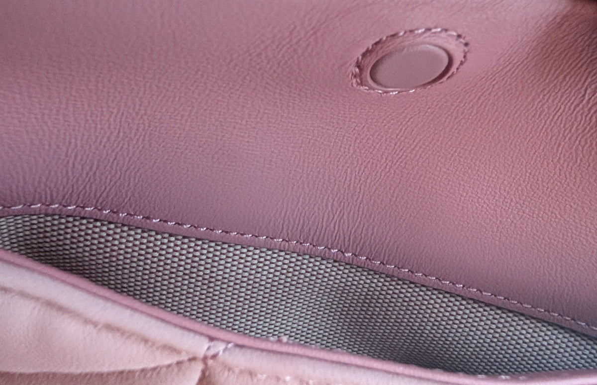 Close-up detail of a pink textured leather or item, showing a circular stitched patch, fine stitching, and a gray mesh interior panel. Pre-Owned Coach Tabby 20 Quilted Nappa Leather Shoulder Bag – Pink & White Ombré
