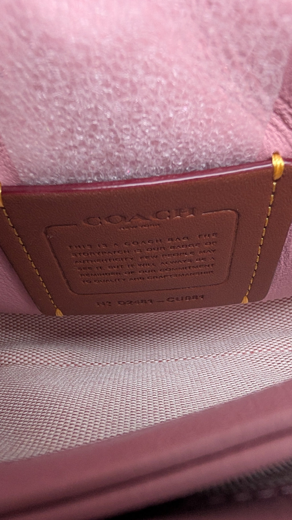 Close-up of a Coach interior detail showing a brown leather interior label stitched onto a dusty pink textured fabric. Pre-Owned Coach Tabby 20 Quilted Nappa Leather Shoulder Bag – Pink & White Ombré