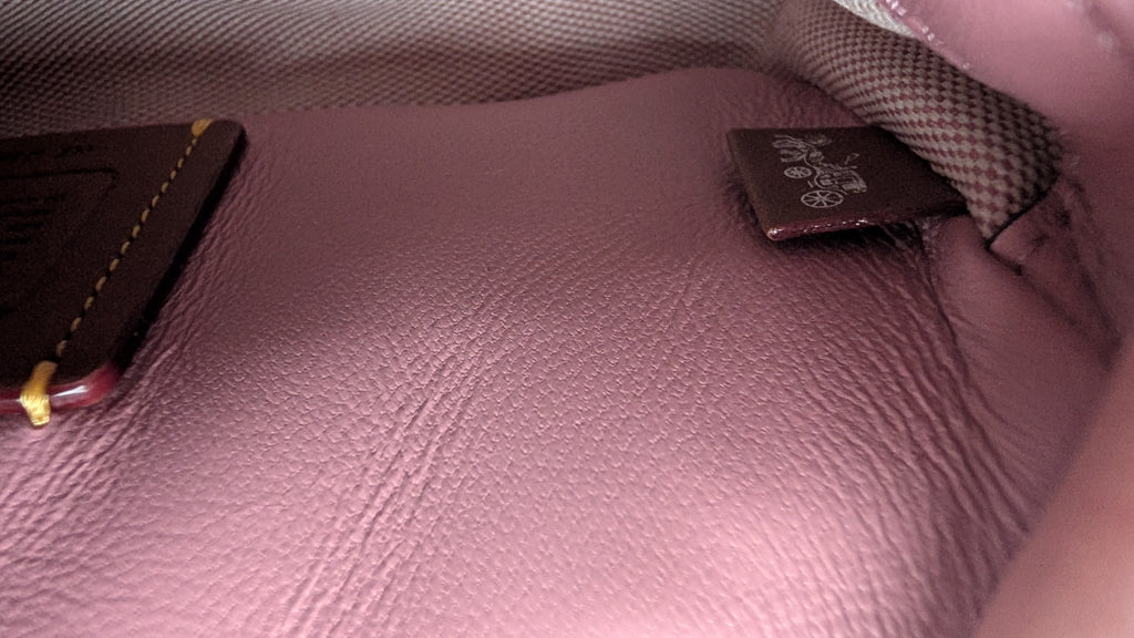 Close-up of the interior lining of a pink textured leather bag, showing a dark brown brand tag  Pre-Owned Coach Tabby 20 Quilted Nappa Leather Shoulder Bag – Pink & White Ombré