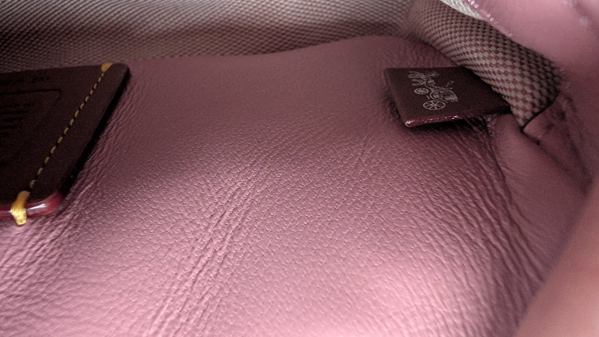 Close-up of the interior lining of a pink textured leather bag, showing a dark brown brand tag  Pre-Owned Coach Tabby 20 Quilted Nappa Leather Shoulder Bag – Pink & White Ombré