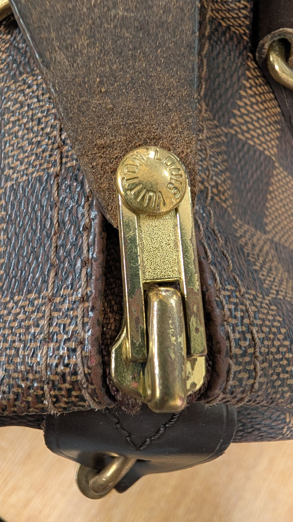 Close-up of a brown monogram canvas bag with a dark brown leather strap and a gold-tone metal clasp. Pre-Owned Louis Vuitton Speedy 25 Damier Ebene Coated Canvas Bag DU4151