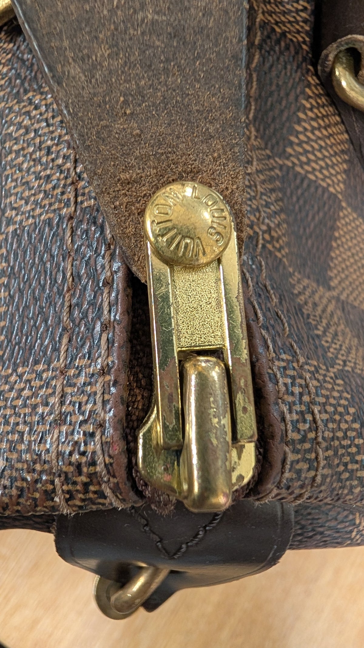 Close-up of a brown monogram canvas bag with a dark brown leather strap and a gold-tone metal clasp. Pre-Owned Louis Vuitton Speedy 25 Damier Ebene Coated Canvas Bag DU4151