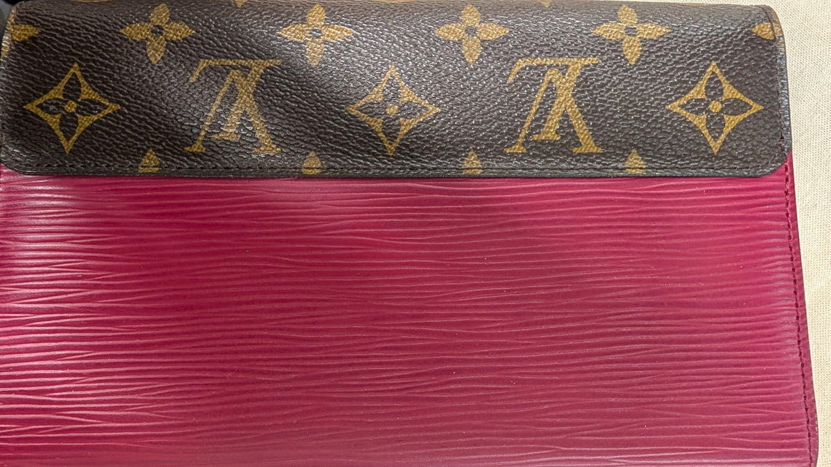 A close-up of a Louis Vuitton wallet or clutch showing the dark brown monogram canvas top with gold LV logos and a bright pink textured lower section. Pre-Owned Louis Vuitton Portefeuille Marie-Rose Clutch Wallet – Fuchsia Epi Leather & Monogram Canvas