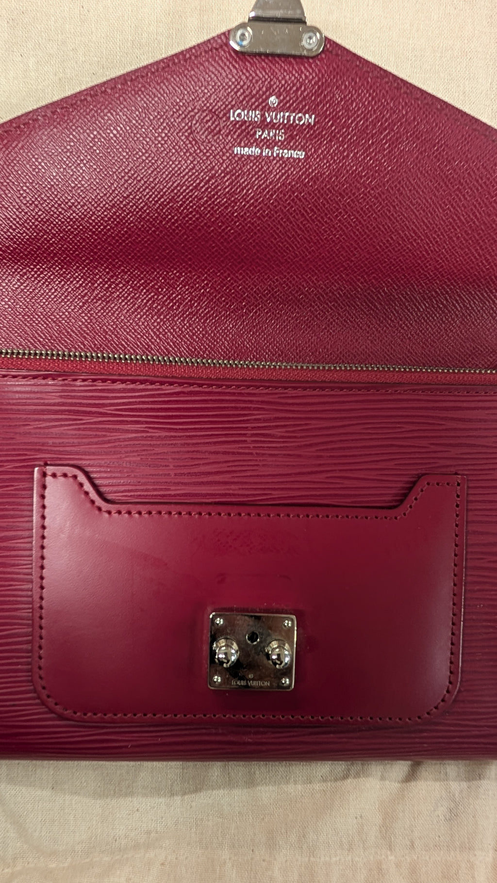 A Louis Vuitton wallet in deep burgundy Epi leather with a silver-tone metal lock and logo on the inside flap, laid flat on a light beige fabric background. Pre-Owned Louis Vuitton Portefeuille Marie-Rose Clutch Wallet – Fuchsia Epi Leather & Monogram Canvas