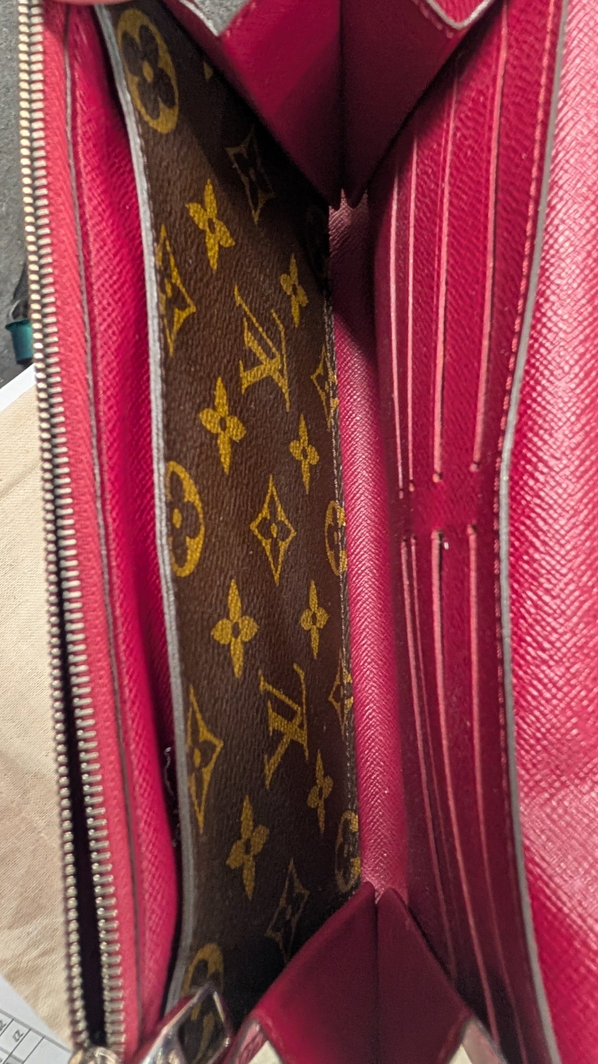 Close-up of the interior of a Louis Vuitton wallet or card case, showing a brown monogram canvas panel with gold-tone LV logos and a bright pink interior lining. Pre-Owned Louis Vuitton Portefeuille Marie-Rose Clutch Wallet – Fuchsia Epi Leather & Monogram Canvas