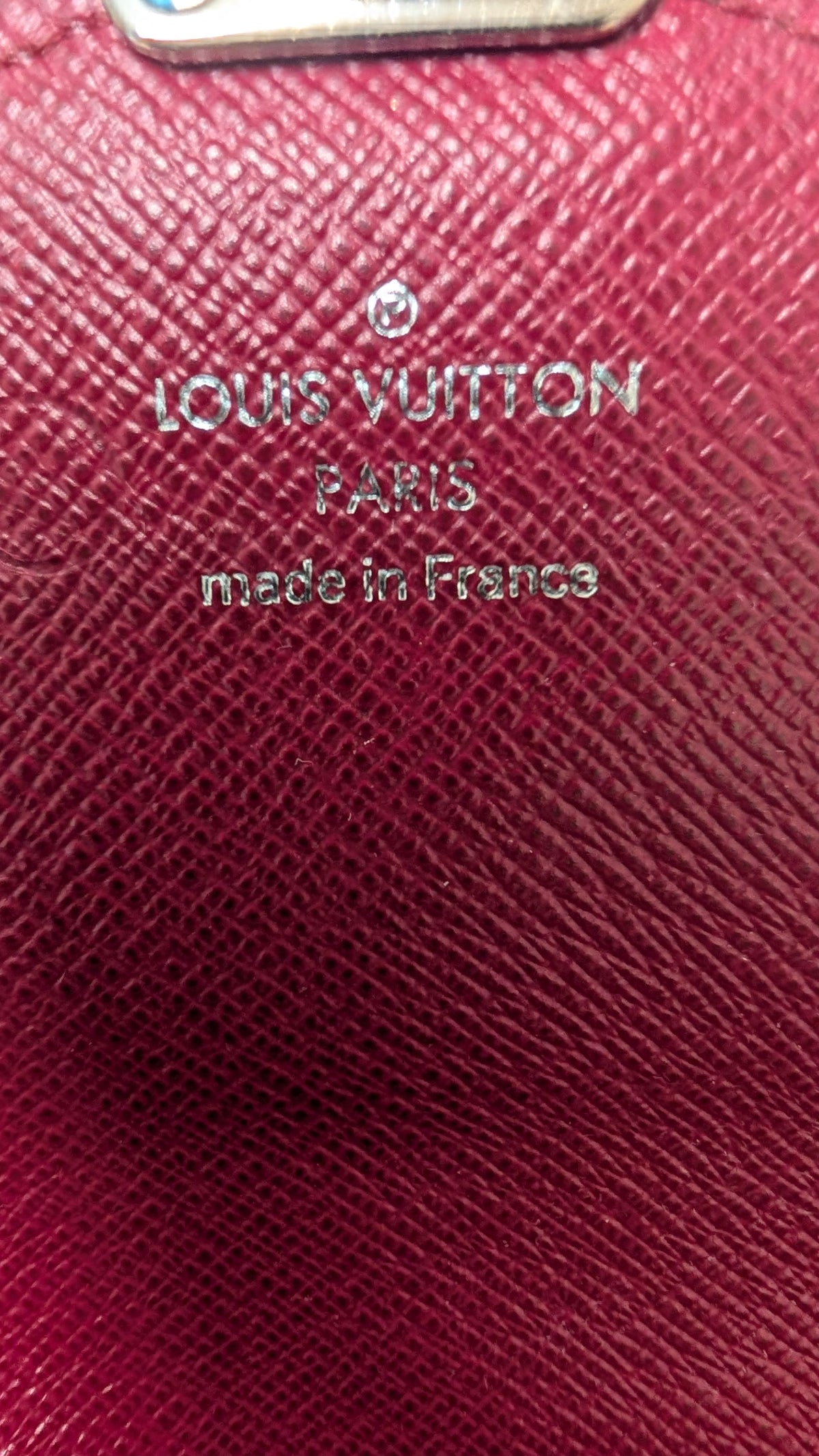 Close-up of a Louis Vuitton Paris made in France card holder or wallet in textured magenta leather with silver-tone branding. Pre-Owned Louis Vuitton Portefeuille Marie-Rose Clutch Wallet – Fuchsia Epi Leather & Monogram Canvas